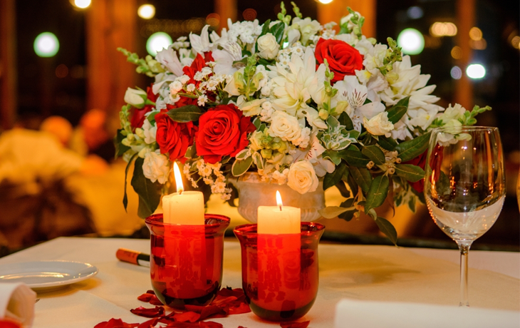 Romantic table setting with red wine, candles, flowers, and soft lighting for a Valentine's Day dinner